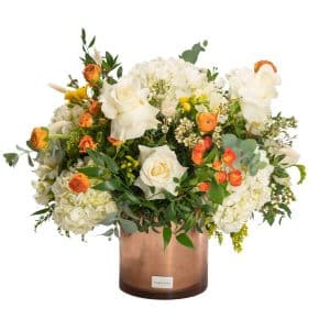floral arrangement with white and orange flowers in golden pot